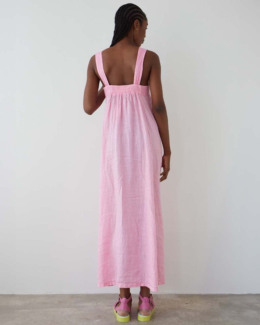 back view of model wearing bubblegum pink cotton maxi dress with square neckline and patch pockets with bright yellow trim