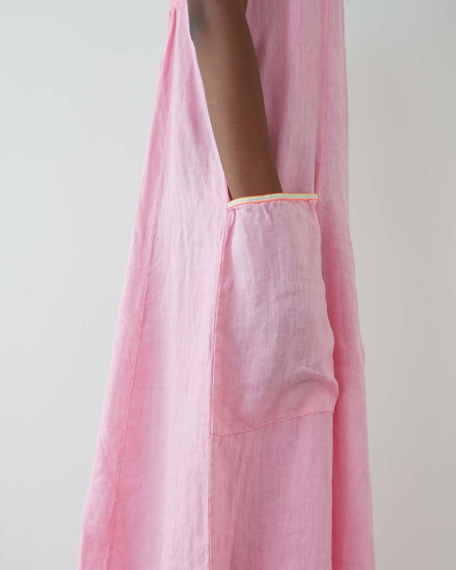 up close of model wearing bubblegum pink cotton maxi dress with square neckline and patch pockets with bright yellow trim