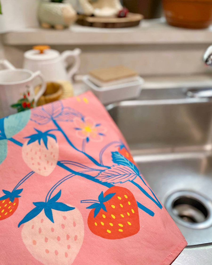 folded pink tea towel with colorful strawberry print 