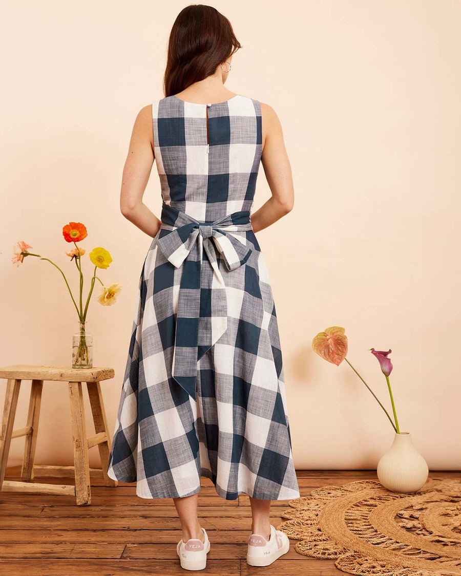 back view of model wearing indigo and white plaid midi dress with wrap waist and thick tank straps