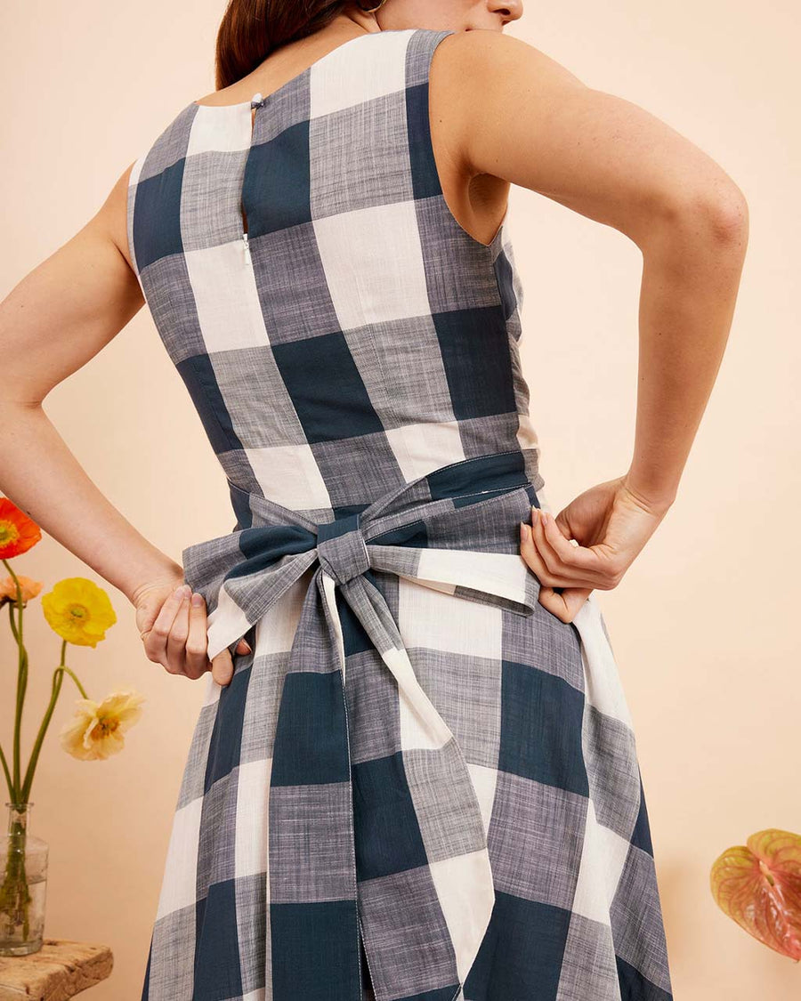 up close of model wearing indigo and white plaid midi dress with wrap waist and thick tank straps