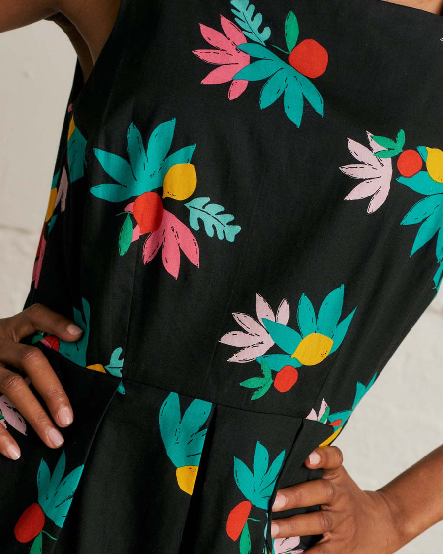 up close of model wearing black tank midi dress with colorful summer fruit print