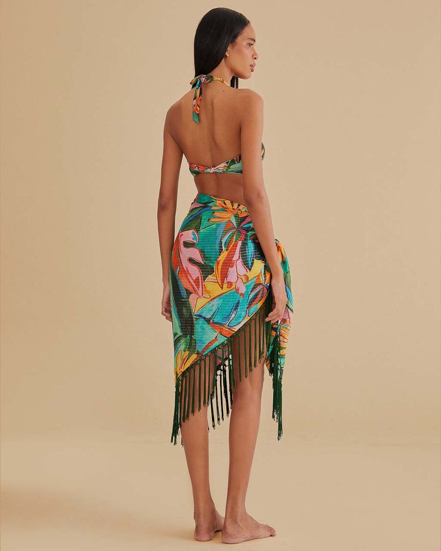 back view of model wearing teal beach sarong with colorful banana and banana leaves print and green fringe