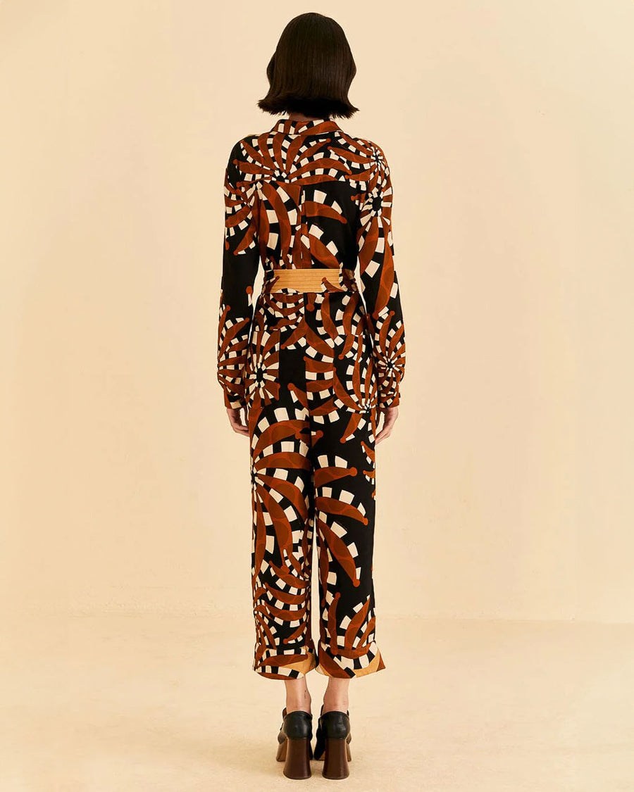 back view of model wearing brown and gold abstract banana jumpsuit with patch pockets on bust and tie waist