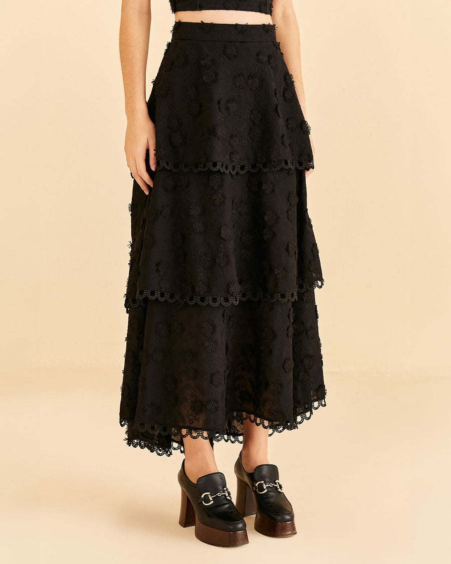 up close of model wearing tiered lace black maxi skirt with 3D flower textured detail and matching top