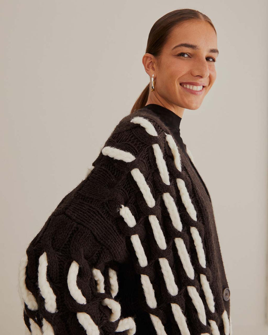 up close of model wearing black oversized cardigan with textured white stripe pattern