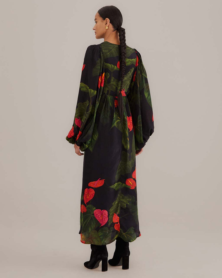 back view of model wearing black maxi dress with puff sleeves, deep v and all over red floral print
