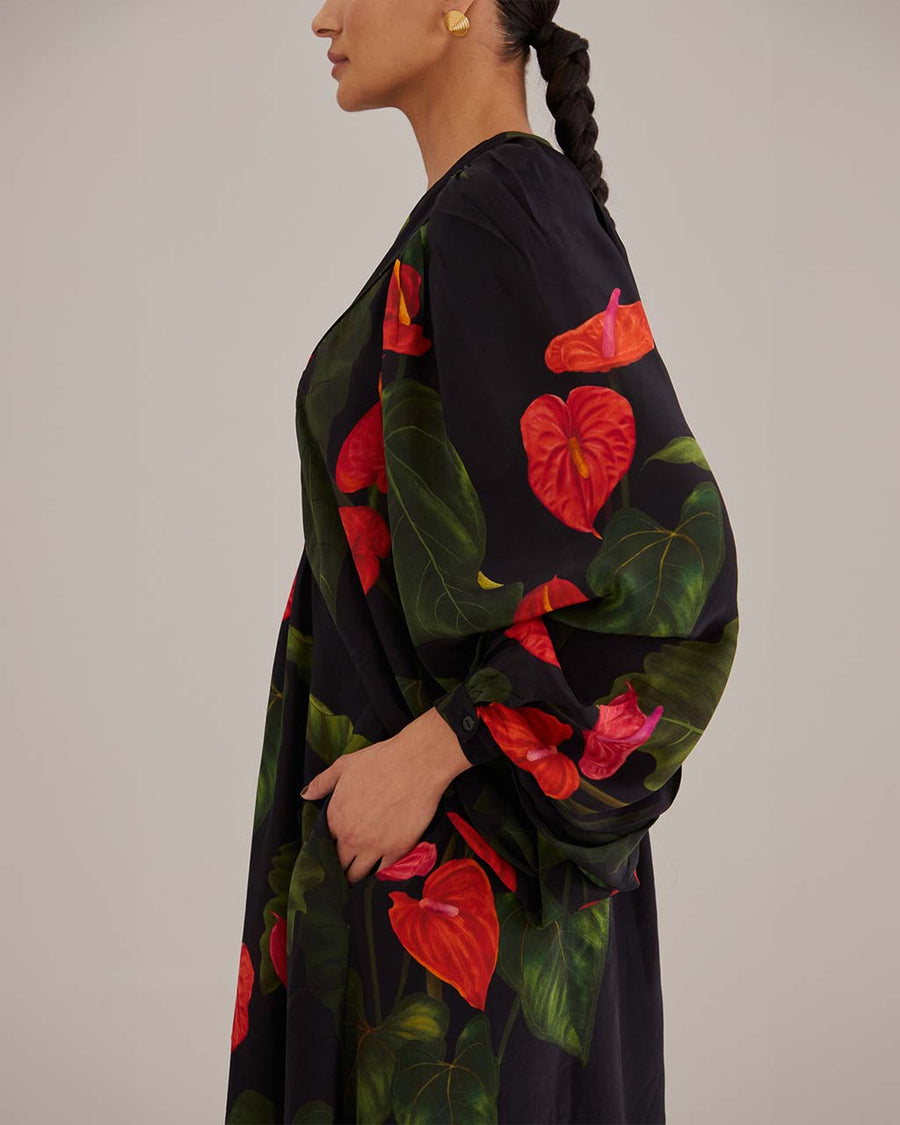 side view of model wearing black maxi dress with puff sleeves, deep v and all over red floral print