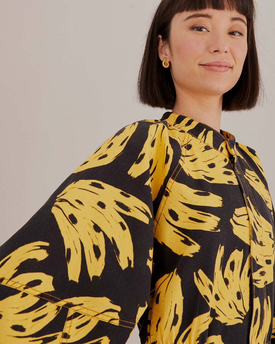 up close of model wearing black long sleeve jumpsuit with abstract banana print
