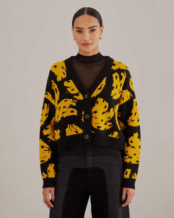 model wearing black cropped cardigan sweater with yellow abstract banana print