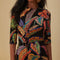 up close of model wearing black midi dress with quarter length sleeves and vibrant foliage print