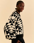 side view of model wearing black and white abstract print sweater with balloon sleeves and slightly cropped fit