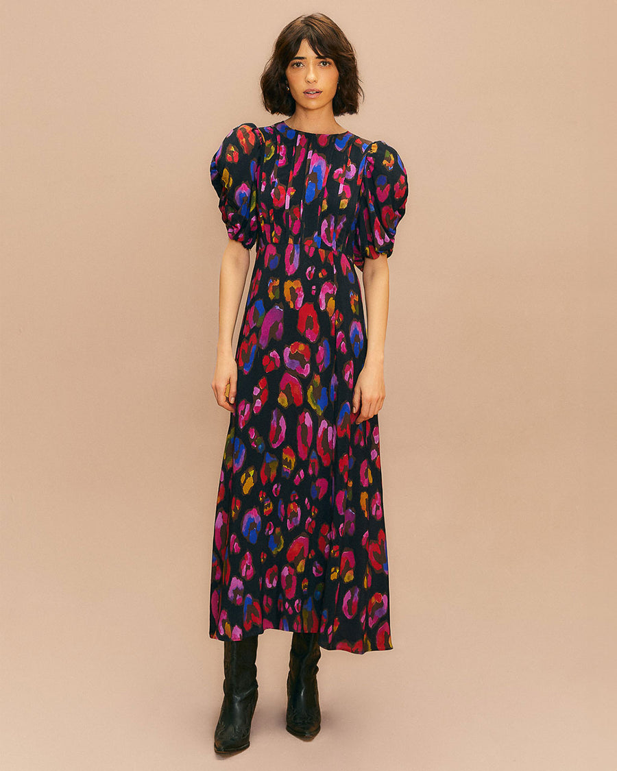 model wearing black midi dress with front slit, shirred puff sleeves and colorful leopard print