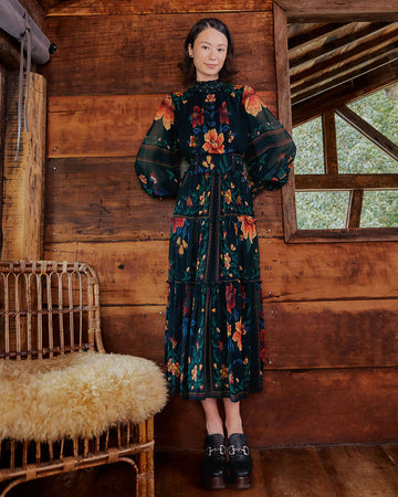 model wearing black midi dress with blouson sleeves and gorgeous colorful floral and macaw print
