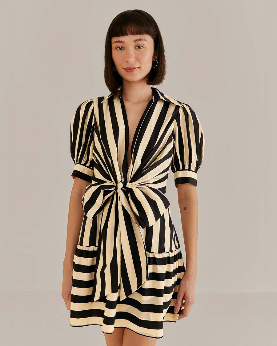 model wearing black and cream stripe mini dress with short sleeves and center bow front