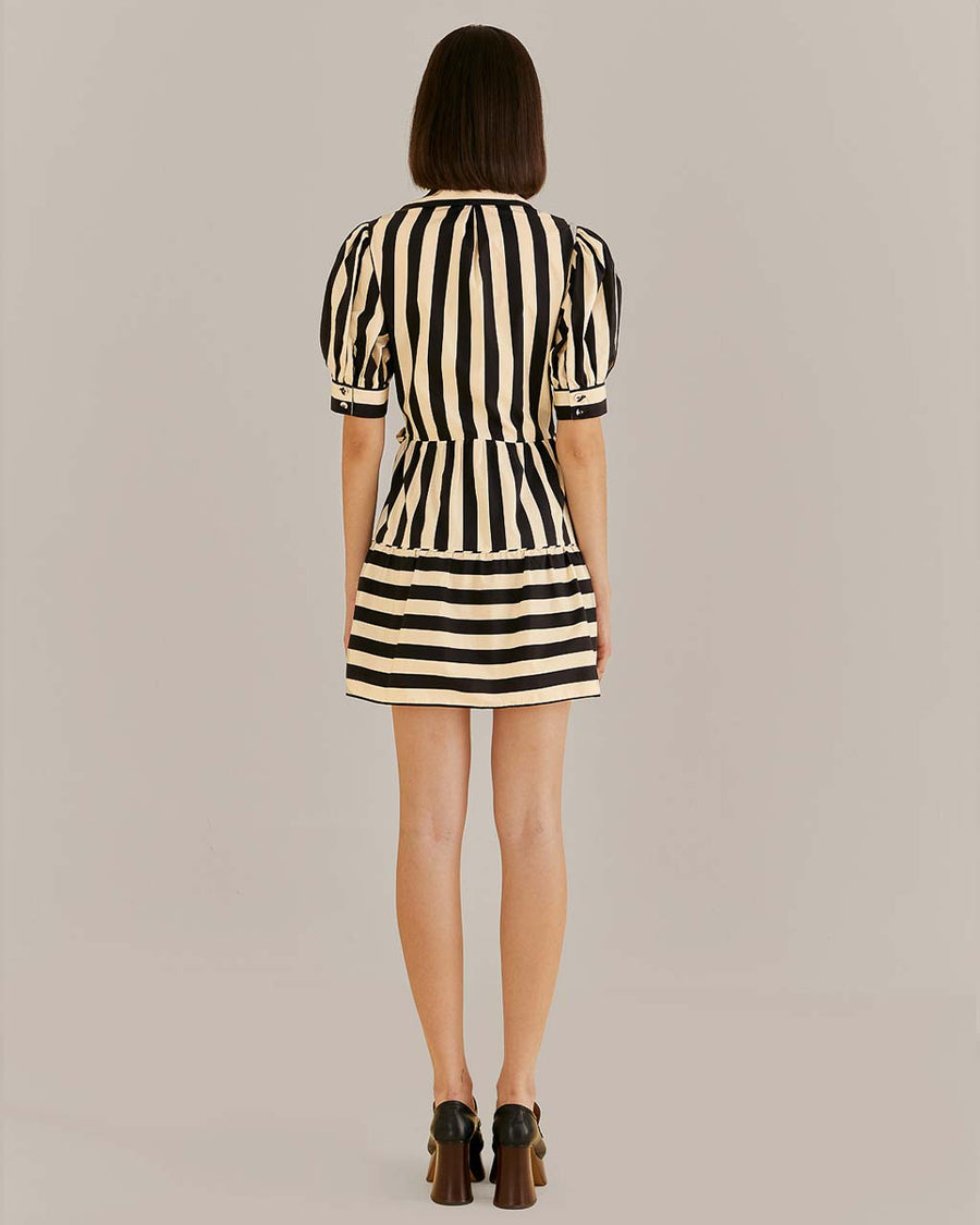 back view of model wearing black and cream stripe mini dress with short sleeves and center bow front