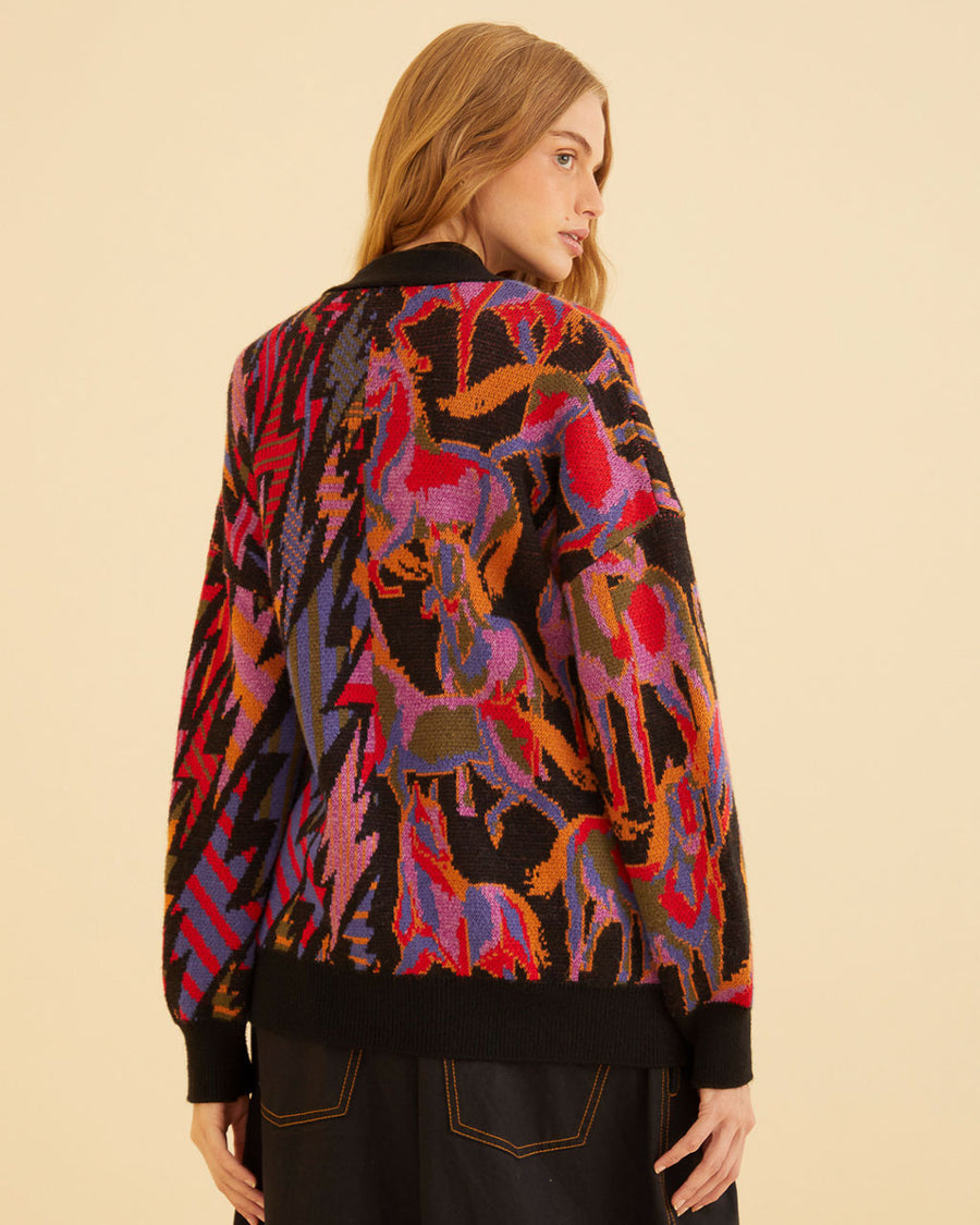 back view of model wearing black cardigan with colorful horse print on one side and vibrant lightning bolt print on the other