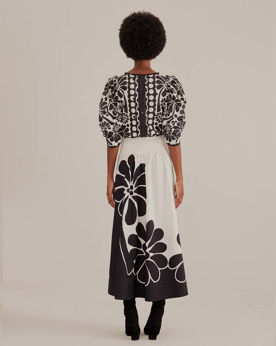 back view of model wearing white midi skirt with black flower print