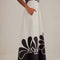 side view of model wearing white midi skirt with black flower print and pockets