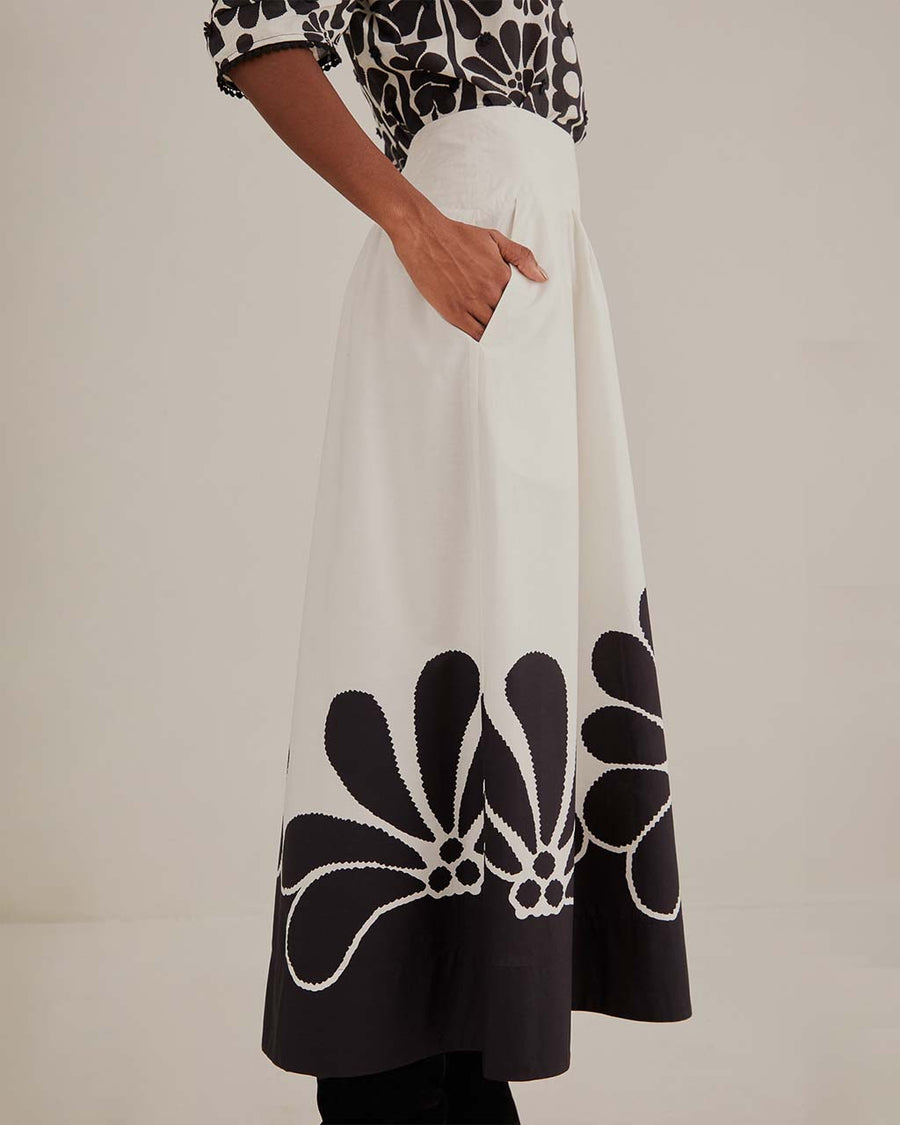 side view of model wearing white midi skirt with black flower print and pockets