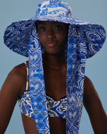model wearing blue and white tile wide brim bucket hat with long tie straps