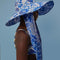 side view of model wearing blue and white tile wide brim bucket hat with long tie straps