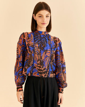 model wearing blue blouse with pleat and ric rac detail down the front and orange tropical print