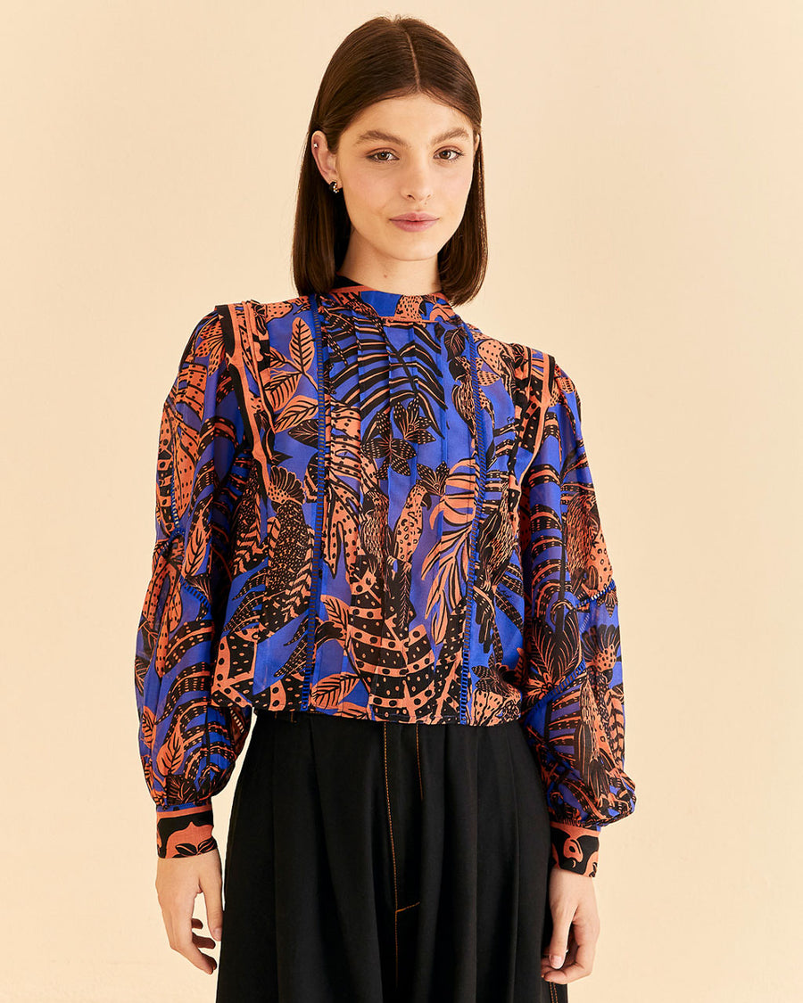 model wearing blue blouse with pleat and ric rac detail down the front and orange tropical print