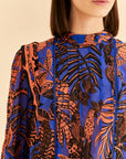 up close of pleat and ric rac detail and vibrant orange tropical print