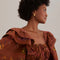up close of model wearing brown maxi dress with ruffle shoulders, puff sleeves and gorgeous colorful horse print