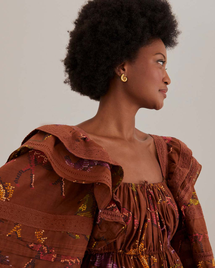 up close of model wearing brown maxi dress with ruffle shoulders, puff sleeves and gorgeous colorful horse print