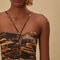 up close of model wearing brown maxi dress with cutout front, tie halter neckline and burnt orange fan print