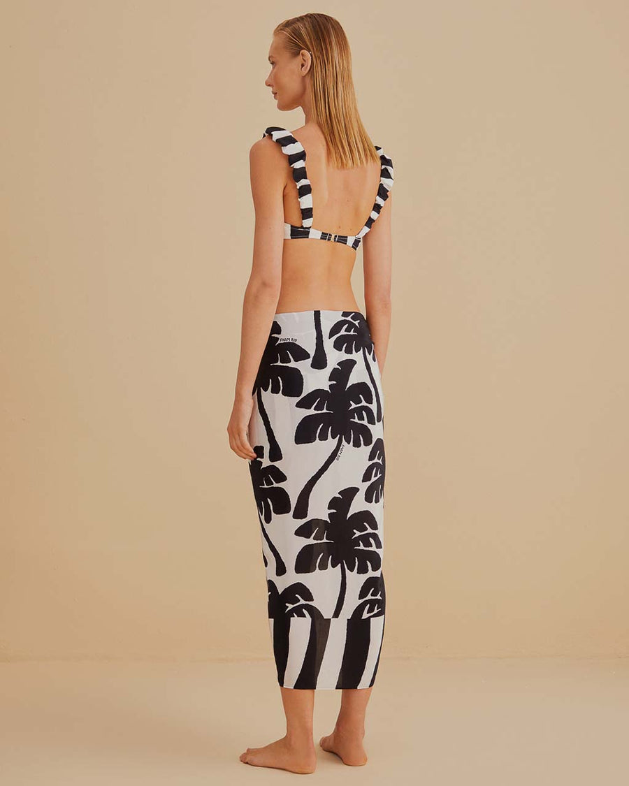 back view of model wearing black and white swim sarong with palm tree print