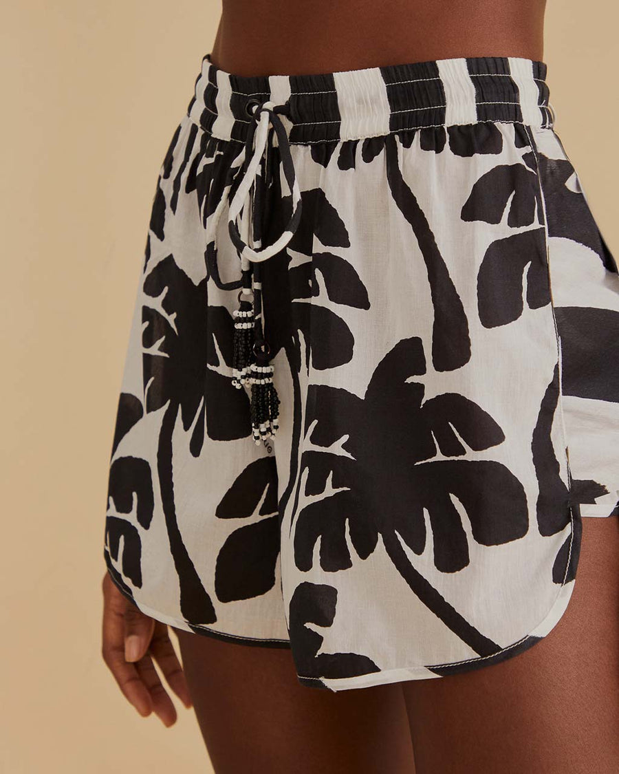 up close of model wearing black and white palm tree print shorts