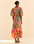 backview of model wearing coral macaw print midi dress with puff sleeves, ruffle bottom and tie waist