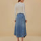 back view of model wearing blue denim midi skirt with wavy button front, and exposed seaming