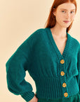 up close of model wearing emerald cardigan with fun tan floral buttons, balloon sleeves and ribbed waist