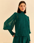 model wearing emerald green blouse with smocked mock neckline, puff sleeves with smocked wrists and pleated front
