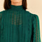 up close of model wearing emerald green blouse with smocked mock neckline, puff sleeves with smocked wrists and pleated front