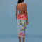 back view of model wearing blue sarong with abstract floral print with tan fringe on the end