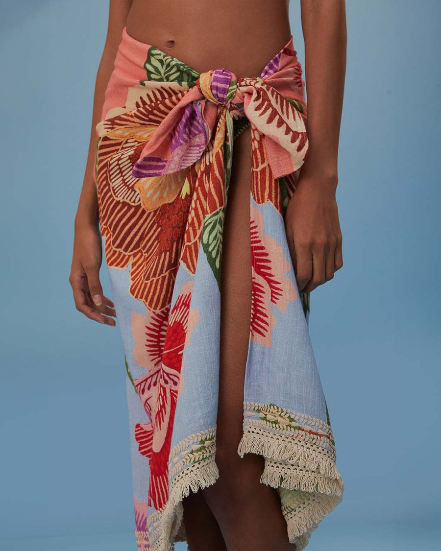 up close of model wearing blue sarong with abstract floral print with tan fringe on the end