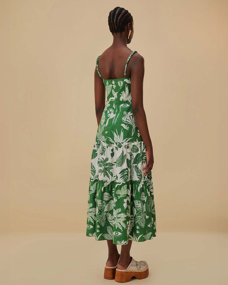back view of model wearing green and white patchwork midi dress with tropical leaf print and tiered skirt