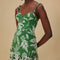 up close of model wearing green and white patchwork midi dress with tropical leaf print and tiered skirt