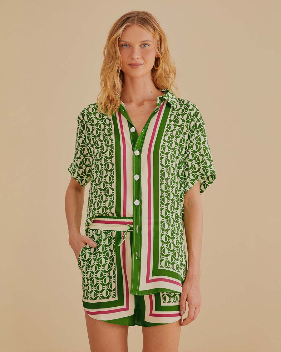 model wearing green short sleeve bottom down top with pineapple print and green, cream and red stripes down the center