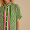 up close of model wearing green short sleeve bottom down top with pineapple print and green, cream and red stripes down the center