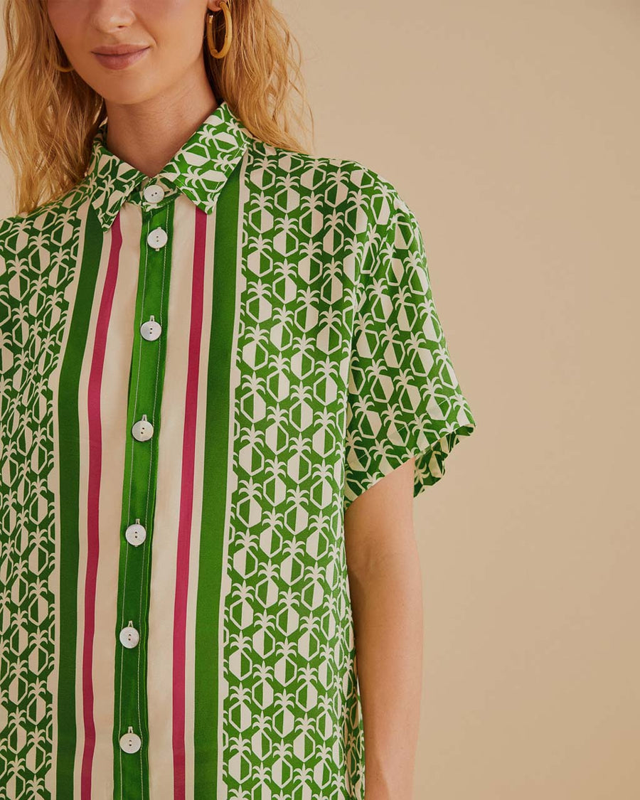 up close of model wearing green short sleeve bottom down top with pineapple print and green, cream and red stripes down the center