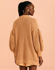 backview of model wearing dark sand open knit cardigan with large button front and blouson sleeves