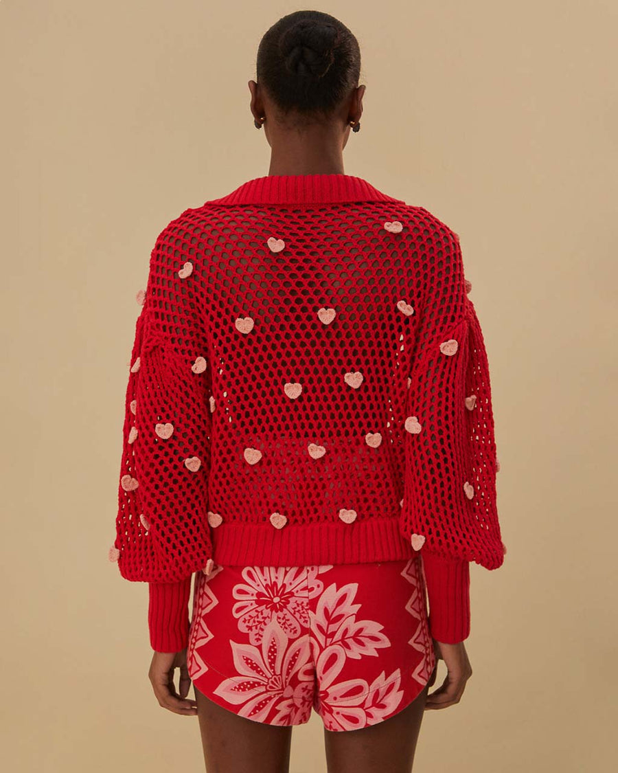 back view of model wearing red open knit crochet sweater with balloon sleeves, collar and small pink appliques