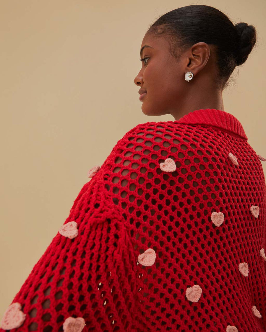 up close of model wearing red open knit crochet sweater with balloon sleeves, collar and small pink appliques
