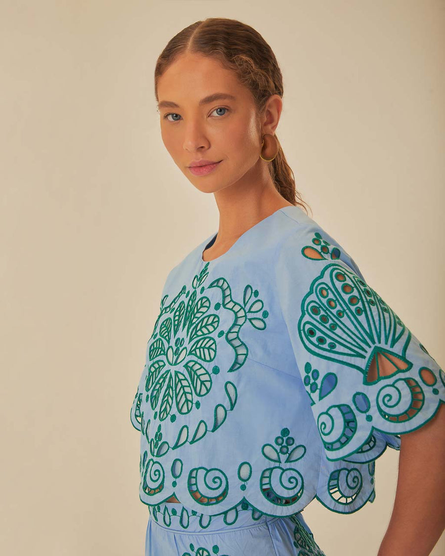 side view of model wearing. light blue cropped top with green cut out design and flutter sleeves